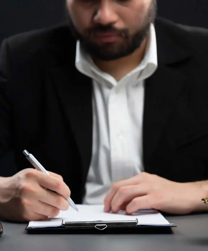 A-man-signing-a-legal-document-at-his-desk