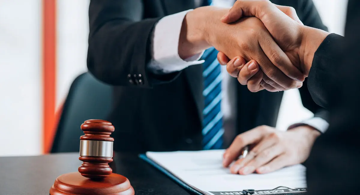 client shaking lawyer's hand at desk