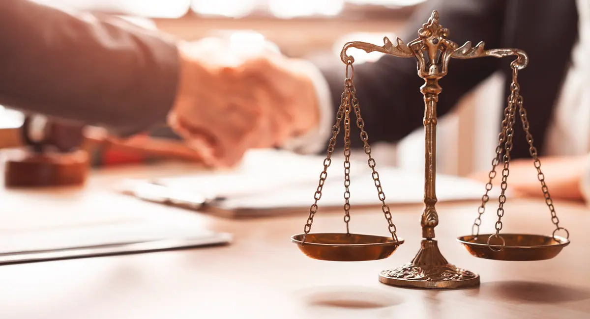 lawyer-and-client-shaking-hands-with-scales-in-foreground