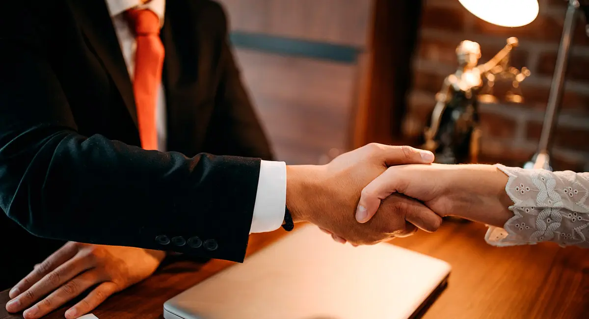lawyer shaking client's hand at desk