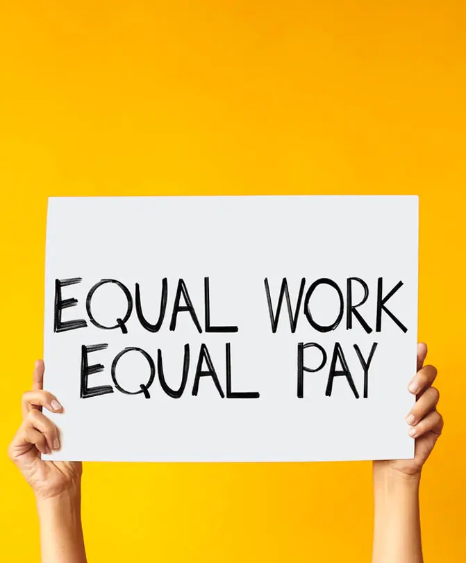 hand-holding-a-sign-reading-equal-work-equal-pay-against-a-yellow-background