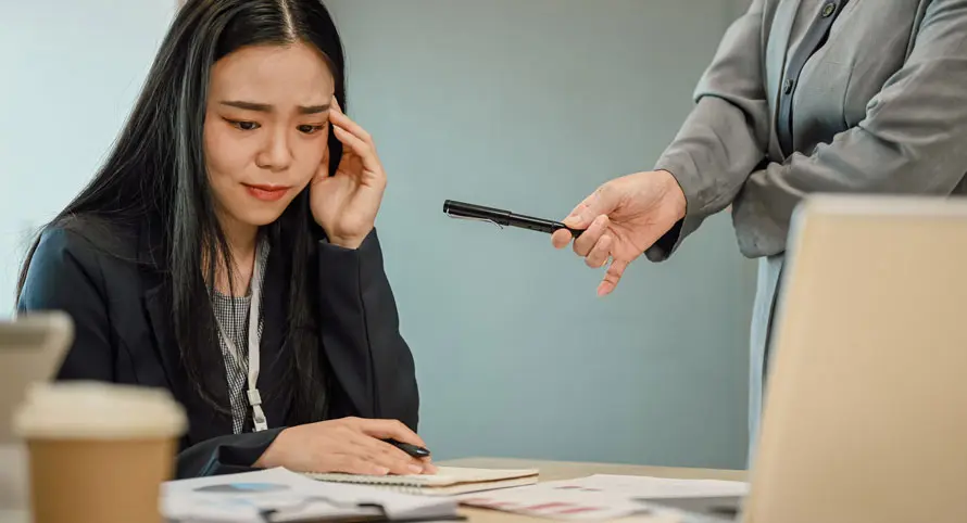 woman-working-at-a-laptop-while-a-colleague-points-at-her-screen