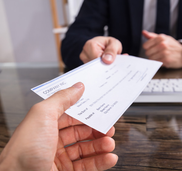 Businessperson-giving-check-to-colleague-at-workplace Businessperson-giving-check-to-colleague-at-workplace