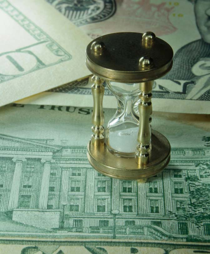 Miniature-hourglass-on-top-of-dollar-banknotes Miniature-hourglass-on-top-of-dollar-banknotes
