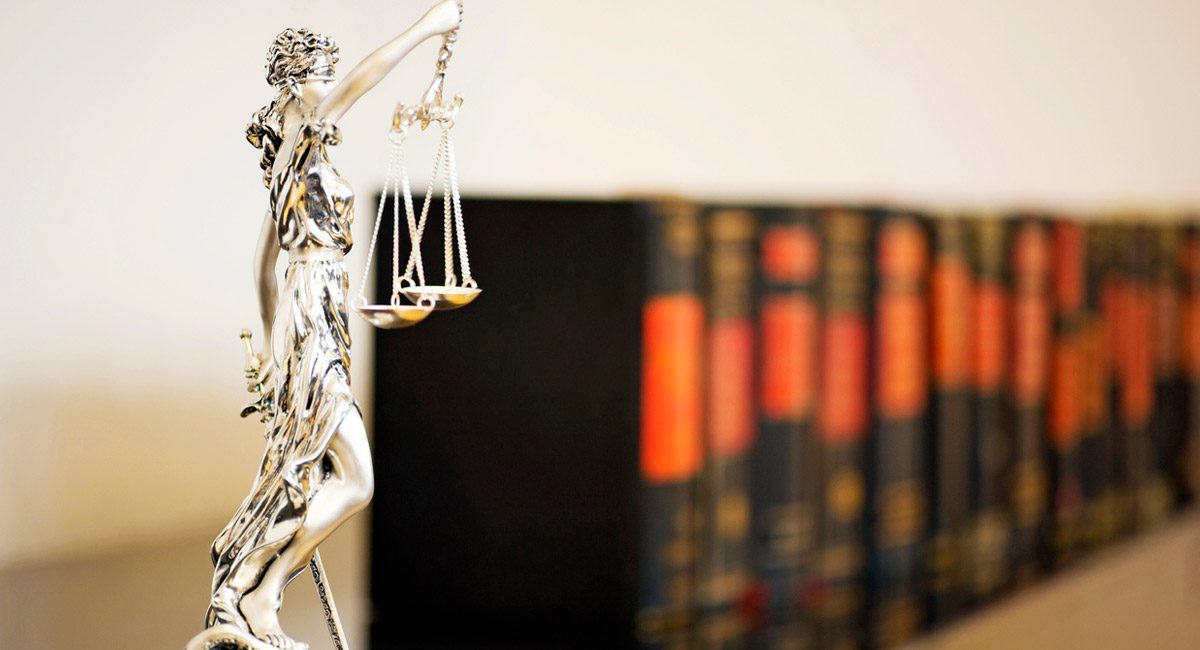 justice statue next to law books on shelf