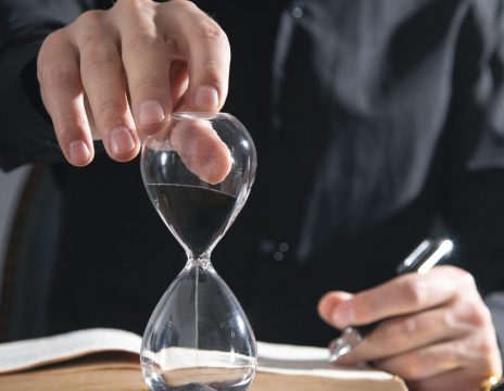 Male person showing hourglass on desk