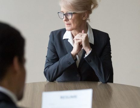 Middle-aged-stressed-woman-sitting-at-the-desk-in-office-at-meeting