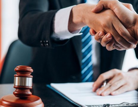 client shaking lawyer's hand at desk