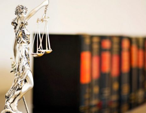 justice statue next to law books on shelf