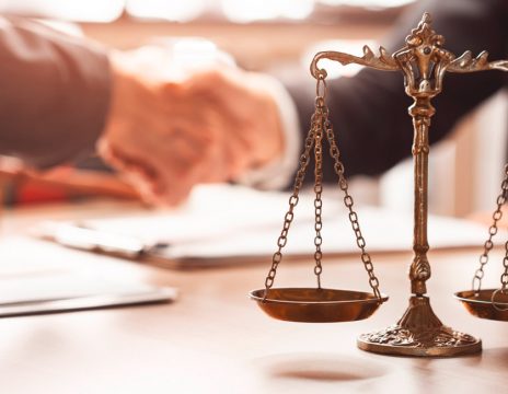 lawyer and client shaking hands with scales in foreground