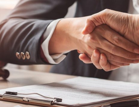 two-people-shaking-hands-over-paperwork-and-a-gavel