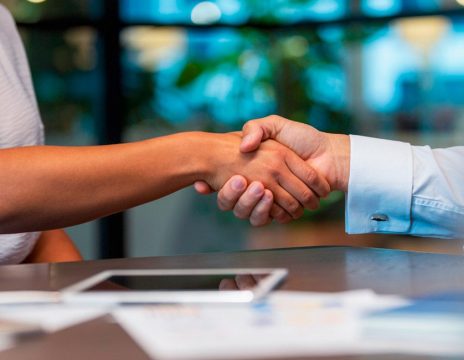 two people shaking hands over table