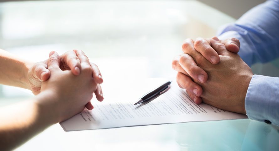 two-people-with-clasped-hands-across-a-table-during-a-discussion